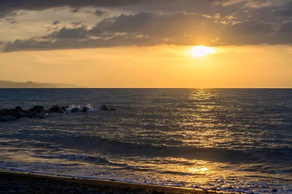 Kıbrıs kıyılarındaki sakin Akdeniz 'in üzerinde güzel bir gün batımı. Altın ışık, deniz dalgaları ve huzurlu bir atmosfer. Doğa, seyahat, deniz manzarası, akşam