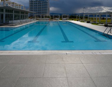 Ferahlatıcı sular çağdaş bir tatil köyünde parıldıyor. Arkaplan bulutlara ve uzak dağlara vuruyor..