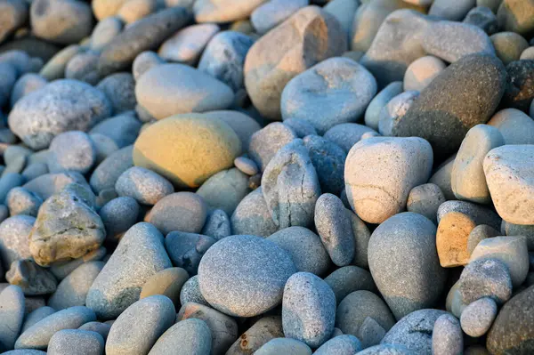 Pürüzsüz, renkli çakıl taşları, ufuk boyunca nefes kesen günbatımının yumuşak renklerini yansıtan, pitoresk bir kıyı şeridi oluşturur..