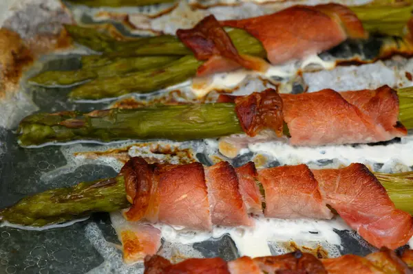 Taze kuşkonmaz mızrakları, kıtır kıtır pastırmaya sarılmış, pişmiş bir tepside cızırdıyor ve kahverengileşiyorlar. Mutfağın sıcaklığı bu lezzetli yemeğin davetkar aromasına katkı sağlıyor..