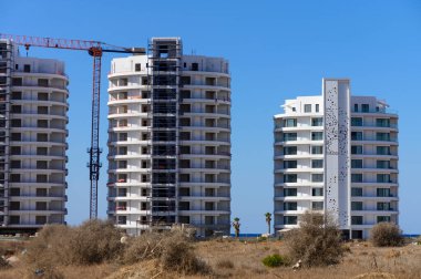 İki modern kıyı kulesi açık bir gökyüzüne karşı yükseliyor, inşaat ilerlemesi ve canlı bir ortam sergiliyor..