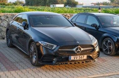 Gaziveren Kıbrıs Rum Kesimi - 30.01.2025 Şık bir siyah lüks sedan iyi ışıklandırılmış bir park alanında diğer araçlar arasında zarif bir şekilde duruyor.