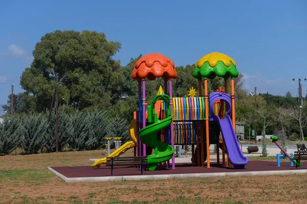 Canlı oyun yapısı slaytlar, tırmanma çerçeveleri ve renkli çatılar, yeşillik ve çocukların eğlence ve macerası için mükemmel bir parka yerleştirilmiş.