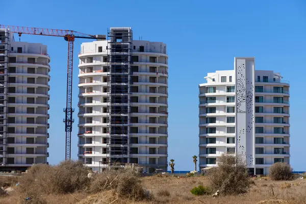 İki modern kıyı kulesi açık bir gökyüzüne karşı yükseliyor, inşaat ilerlemesi ve canlı bir ortam sergiliyor..