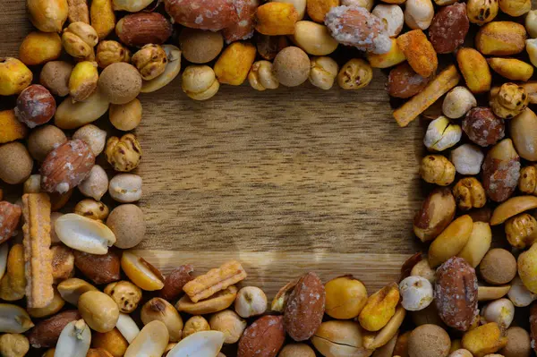 Çeşitli fındık ve abur cuburlardan oluşan canlı bir koleksiyon kırsal ahşap masa üstünde davetkar bir sınır oluşturur..