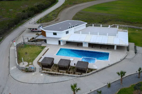 Çağdaş bir bina ve yemyeşil bir havuzun olduğu huzurlu bir dinlenme yeri..