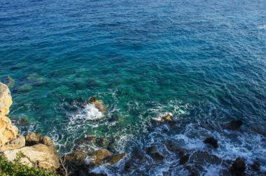 Dalgalar yavaşça kayalara çarpıyor. Sıcak bir günbatımı gökyüzünün altında ışıldıyor. Huzur ve güzelliği çağrıştırıyor..