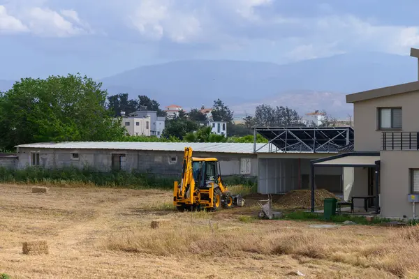 Kıbrıs 'ta geleneksel bir köy evinin yakınına park edilmiş parlak sarı bir traktör ve arkasında çarpıcı dağlar var. Resmedilmeye değer kırsal bir manzara Akdeniz yaşamını gözler önüne seriyor.