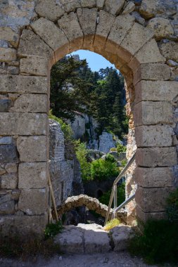 St. Hilarion Kalesi 'nin taş kemeri tarafından çerçevelenmiş göz kamaştırıcı bir manzara, çevresindeki manzarayı ve uzak dağları bir anlığına gösteriyor..