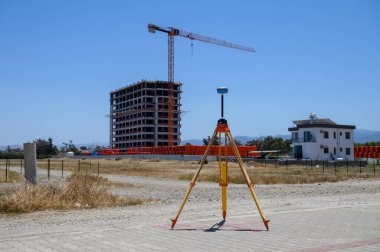 Kıbrıs Rum Kesimi 'nde güneşli bir günde inşaat sahasının yakınındaki GPS' li jeodetik teodolit.