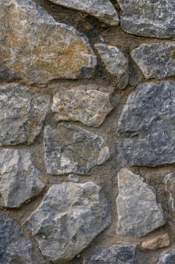 Eşsiz doku ve renklere sahip, doğal maddelerin güzelliğini vurgulayan engebeli bir taş duvarın ayrıntıları.