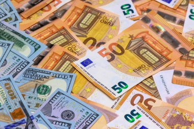 Çeşitli banknotların karmaşık detayları masanın üstünde canlı bir duvar halısı oluşturur, kültürleri ve ekonomileri harmanlar..
