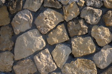 Yıpranmış taşlar, doğayı ve işçiliği harmanlayan parlak bir zemin üzerine toprak dokusunu sunar..