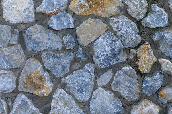 Taşlar, doğanın sanatsal özelliklerini vurgulayan gri ve toprak tonlarının güzel bir karışımını sergileyen kırsal bir duvar oluşturur..