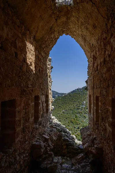 Kuzey Kıbrıs 'taki St. Hilarion Kalesi' nin taş penceresinden dağların ve denizin manzarası. Doğa tarafından çerçevelenmiş tarihe bir bakış..