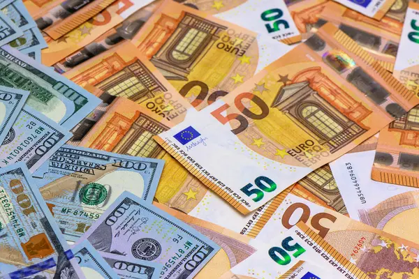 Çeşitli banknotların karmaşık detayları masanın üstünde canlı bir duvar halısı oluşturur, kültürleri ve ekonomileri harmanlar..