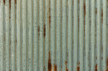 Dikey metal paneller güneş ışığına karşı bir doku ve renk karışımı sergiler, aşınma ve yıpranma tarihini ortaya çıkarır.