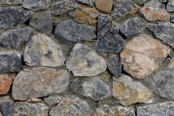 Engebeli taş bir duvar, zengin bir renk ve şekil duvar halısı sergiliyor. Seyircileri, doğanın malzemelerinin ve işçiliğinin organik güzelliğini takdir etmeye çağırıyor..