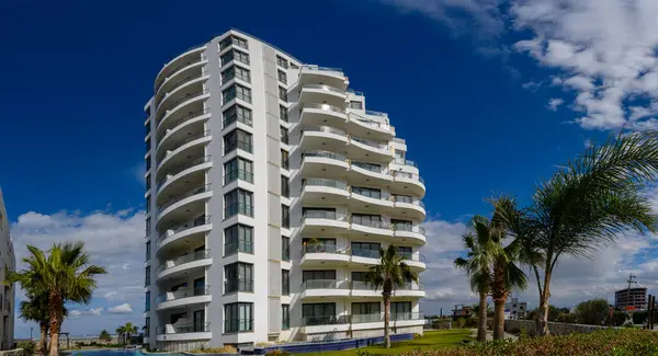 Çarpıcı bir modern bina, eşsiz tasarımını canlı mavi gökyüzüne karşı sergiliyor. Bereketli palmiye ağaçları manzarayı benekler, bu kıyı inzivasının tropikal atmosferini güçlendirir..