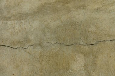 Toprak tonlarının bir karışımı çatlak bir alçı duvarı sergiliyor, dokusunu ortaya çıkarıyor ve zamanla aşınıyor..