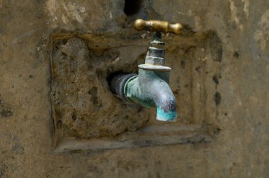 Kıbrıs 'ın dışındaki taştan bir lavabodaki klasik bronz musluk, patina ve Akdeniz cazibesini gösteriyor.