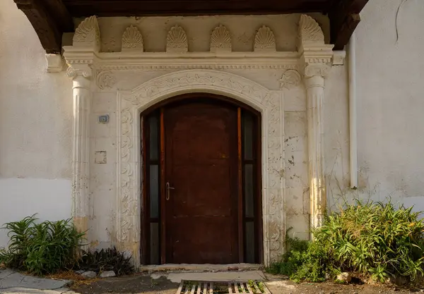 Kıbrıs 'ta beyaz duvarları olan bir evin eski kemerli taş kapısı, geleneksel Akdeniz mimarisini yansıtıyor.