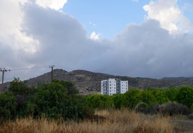 Akdeniz manzarası ve mavi gökyüzü ile çevrili, Kıbrıs 'taki bir dağın eteklerine kurulmuş geleneksel beyaz ev.