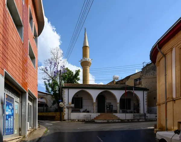 Kıbrıs 'ın Lefke kentindeki tarihi cami, yerel binalar ve dağlarla çevrili uzun bir minare ve geleneksel İslami mimariye sahip.
