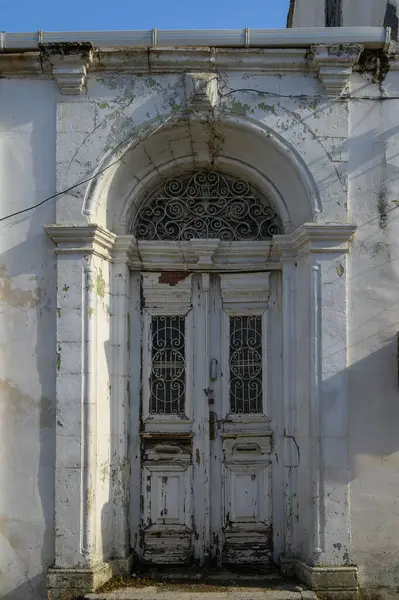 Yıpranmış ahşap kapılar ve taş kemer, yerel mimari ve kırsal çekiciliğin yer aldığı geleneksel Kıbrıs Rum evinin girişini işaret ediyor.