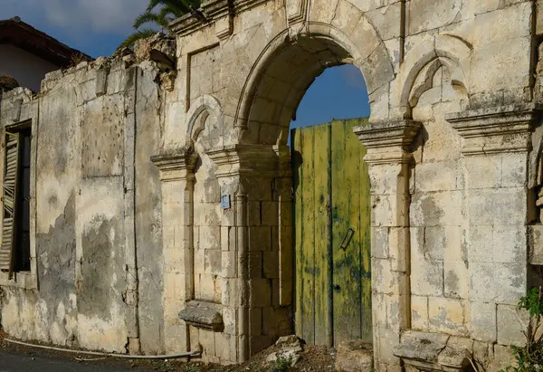 Geleneksel Kıbrıs Rum ev duvarı, taştan yapılmış ve kırsal Akdeniz tarzını yansıtan eski ahşap kapılara sahip..