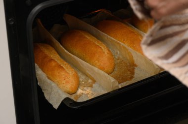 Taze şekilli Graham ekmeği somunları fırında yükseliyor ve altın rengine dönüyor, bir ev mutfağında pişirme işlemi sırasında yakalandı..