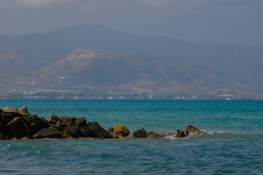 Kıbrıs kıyılarında açık gökyüzü altındaki uzak dağlarla Akdeniz 'in panoramik yaz manzarası.