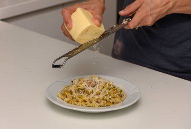 Ev yapımı bir aşçı peyniri makarna üzerine ızgara yapar. Sıcak ve davetkar bir mutfak ortamında nefis bir ev yemeği yapar..