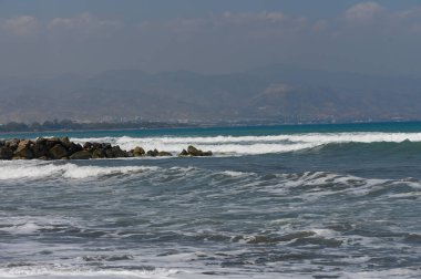 Kıbrıs 'ın kumlu plajından Akdeniz manzarası sakin. Temiz su ve ılık yaz ışığı.