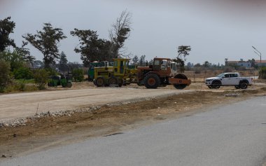 Kıbrıs Rum Kesimi 'nin tepeleri ve kırsal kesimlerinde parlak güneş altında yeni bir yol üzerinde inşaat araçları çalışıyor.