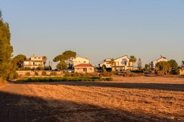 Sıcak gün batımı ışığında yıkanan geleneksel bir Kıbrıs köyünün resimli görüntüsü. Akdeniz evleri,