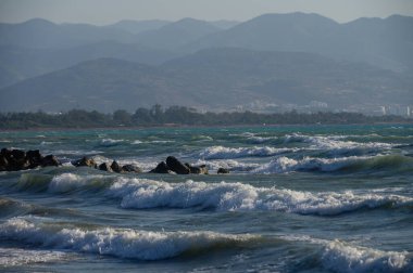 Akdeniz 'in güzel dalgaları ufukta dağ manzaralı. Mükemmel seyahat yeri ve doğal tatil geçmişi.