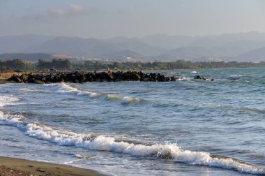 Akdeniz 'in yumuşak yaz dalgaları Kıbrıs' ın kumlu kıyılarına ulaşarak güneşi yansıtıyor ve huzurlu bir tatil havası yaratıyor.