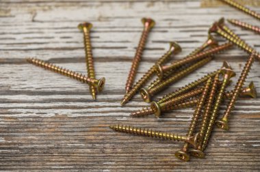 Bronz renkli vidalar eski ahşap bir masaya saçılmış. İnşaat, DIY ve donanım fotoğrafçılığı için mükemmel..