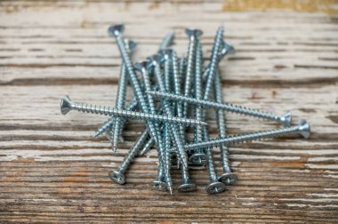 Ahşap bir masaya saçılmış parlak metal vidalar yakın plan, DIY, atölye ve inşaat fotoğrafçılık için ideal.
