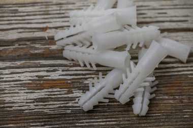 Eski ahşap bir masaya saçılmış beyaz plastik genişletme duvar bujileri yakın plan, DIY, inşaat ve donanım fotoğrafçılık için mükemmel.