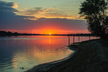 Volga Nehri 'nde yaz günbatımında altın gökyüzü ve durgun suda renkli yansımalarla. Akşamları Rusya 'nın huzurlu doğa manzarası.