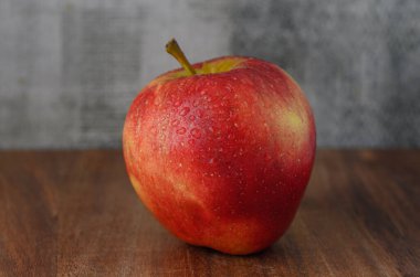 Tahta masada su damlaları olan taze kırmızı elma. Doğal meyve, sağlık, tazelik ve sağlıklı beslenmenin sembolü..