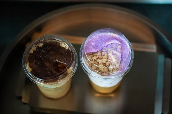 Bir bardak buzlu kahve, taro sütlü ve buzlu cappucino, bir kahve dükkanının çiğ çimento masasında yaz terasında, menü fotoğrafçılığı..