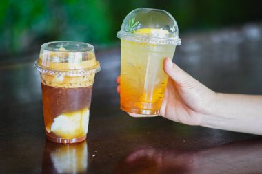 Kahve dükkanında elinde buzlu, soğuk, portakal şurubu aromalı, ballı ve buzlu hindistan cevizli kahve ile karışık kahve tutan bir kadın..