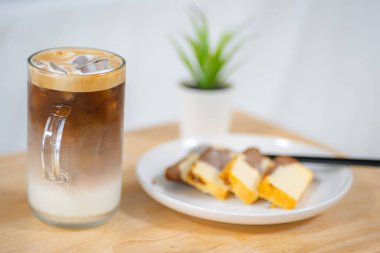 Tahta masada tereyağlı kek ile buzlu latte kahvenin yan görüntüsü.