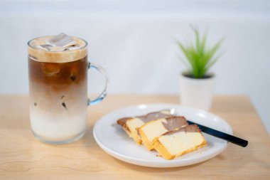 Tahta masada tereyağlı kek ile buzlu latte kahvenin yan görüntüsü.