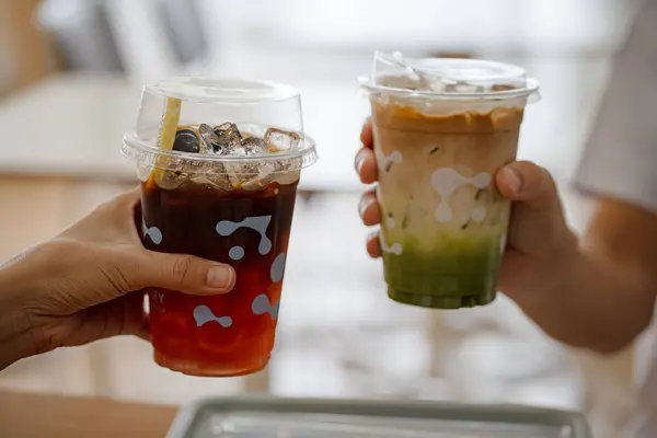Ellerinde bir bardak buzlu çay, limonlu buzlu kahve ve kafede birlikte kibrit yeşil çay tutan genç kız ve erkeğin elleri..