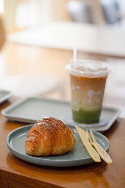 Kahve dükkanının ahşap masasında kruvasan var..