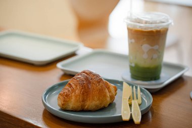 Kahve dükkanının ahşap masasında kruvasan var..